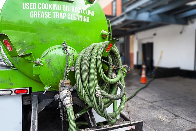 worker pumping grease trap at commercial kitchen in Ceres, CA